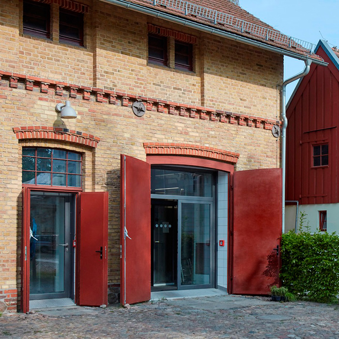 Aussenaufnahme des alten Steingebäude mit roten Holztüren