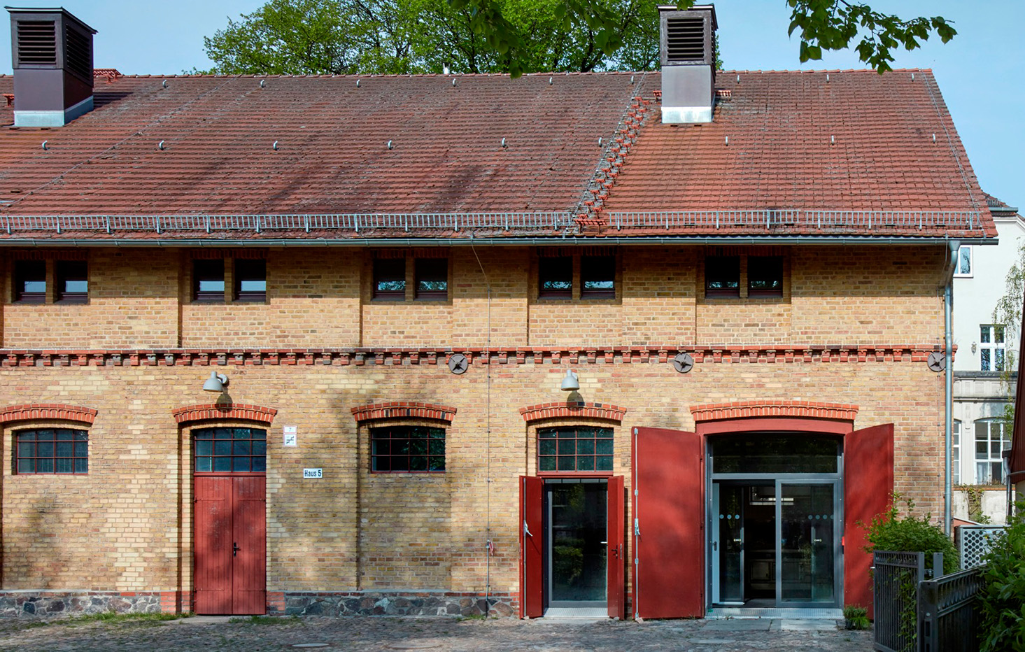 Aussenaufnahme des alten Steingebäude mit roten Holztüren