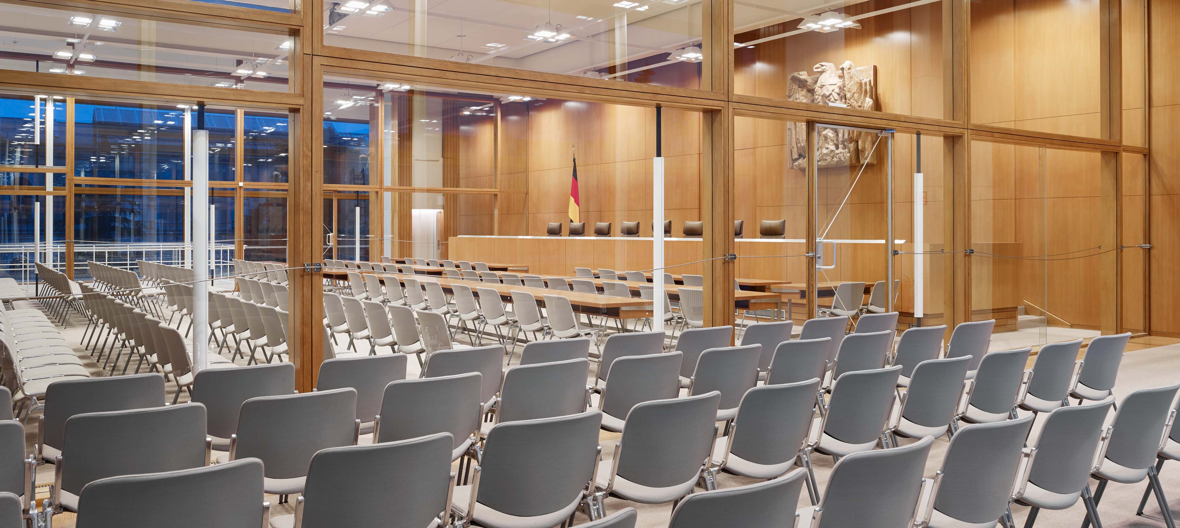 Innenaufnahme eines Verhandlungssaals im Bundesverfassungsgericht mit vielen Sitzreihen mit grauen Stühlen